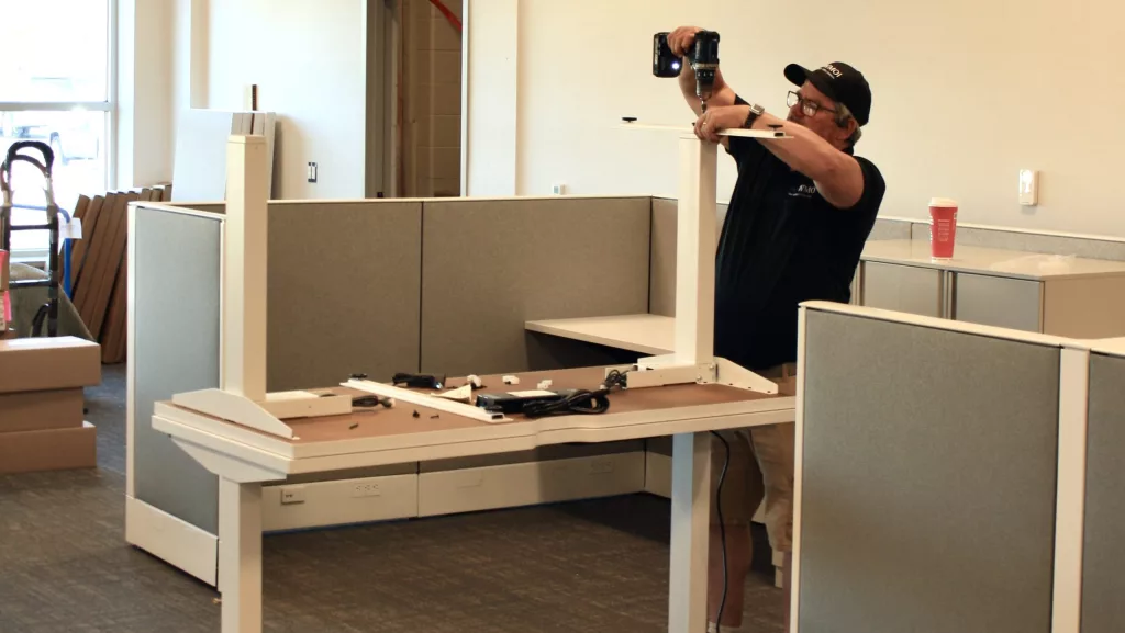Member of WMOI installation team assembling a desk for a workstation