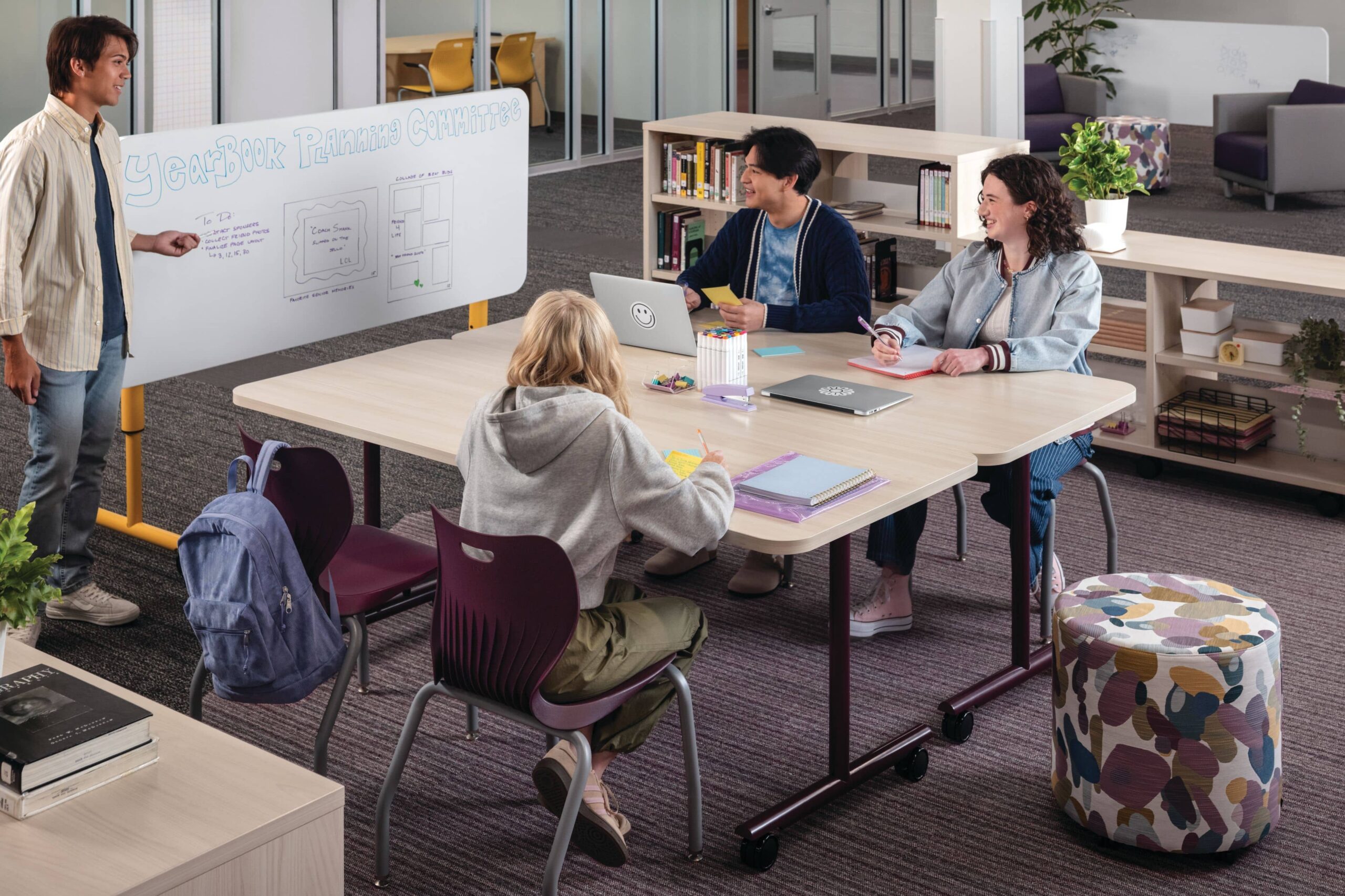 Students collaborating at a classroom table with mobile furniture and whiteboard
