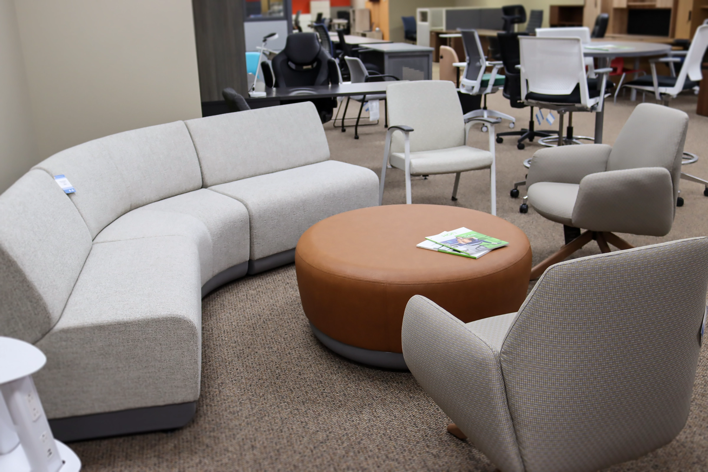 Lounge seating area inside the Kalamazoo showroom with a curved sofa, upholstered chairs, and a round table