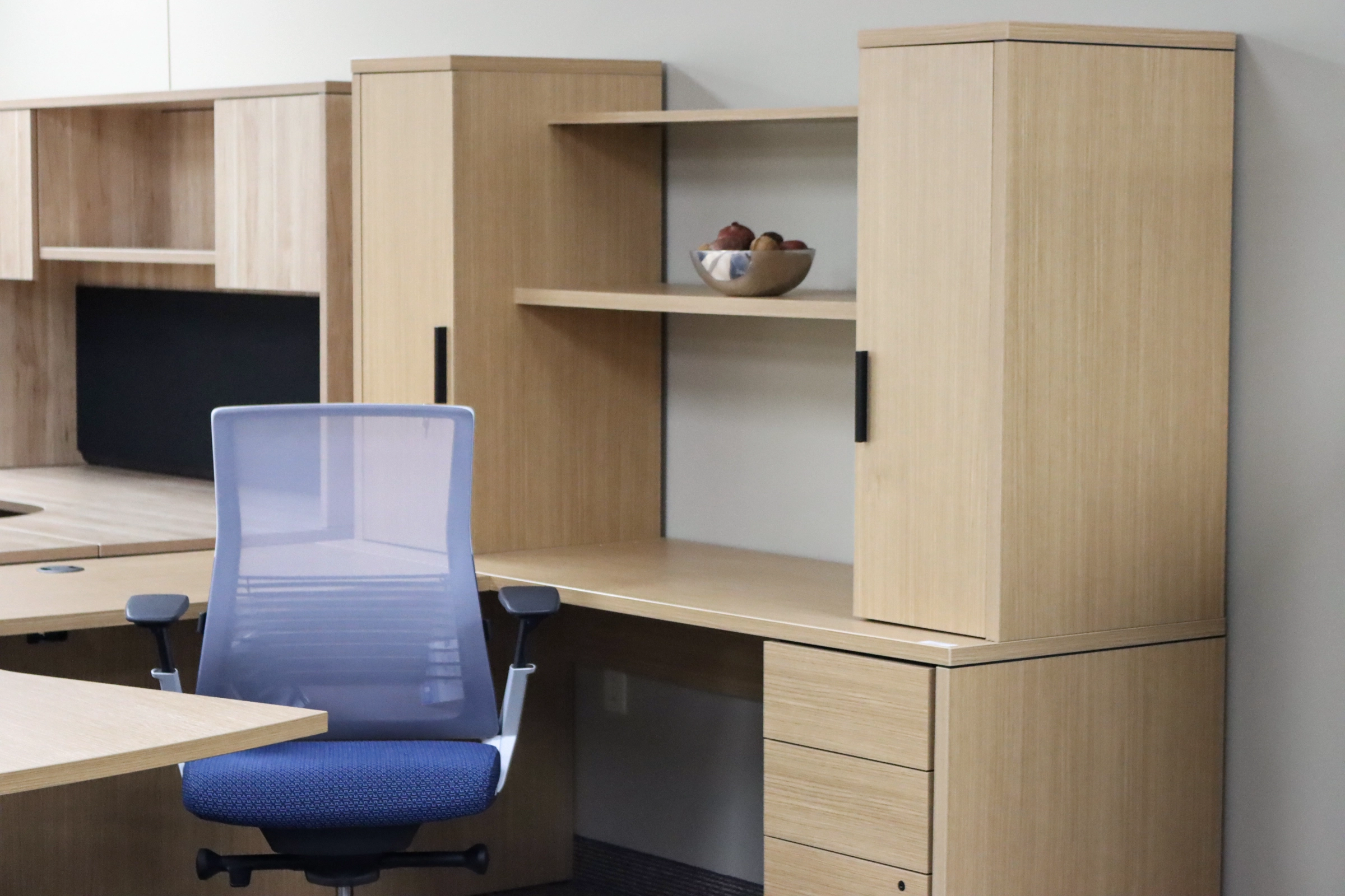 Private office workstation display in the Kalamazoo showroom with wood desk, storage cabinets, and ergonomic chair