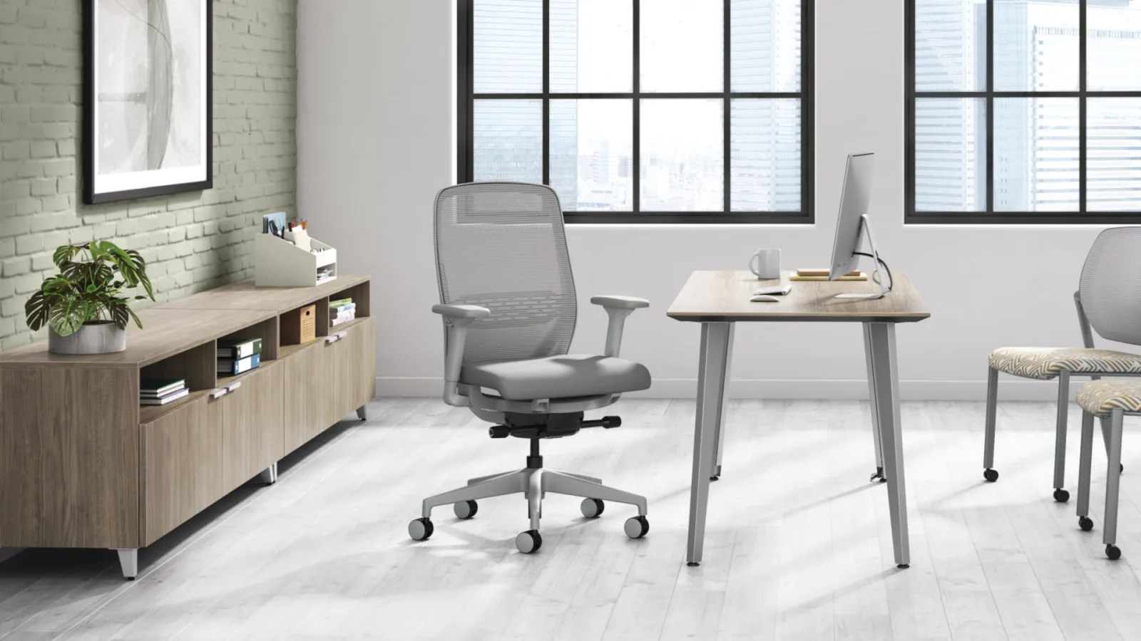 HON Voi laminate desk with metal legs in a modern office, paired with a mesh task chair and low storage credenza.