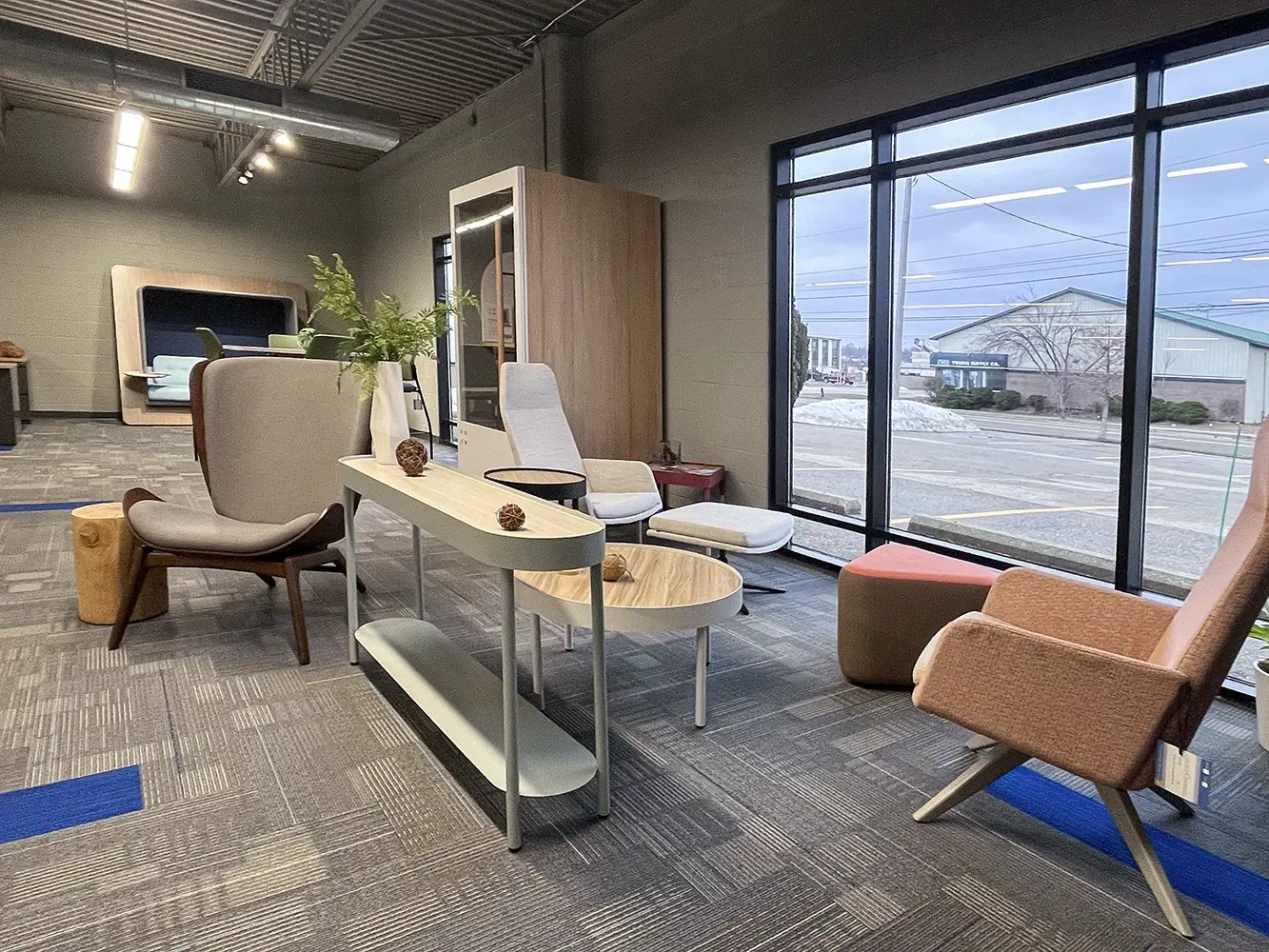 Office seating display inside the Holland, MI showroom, showing a variety of chairs arranged on white platforms.