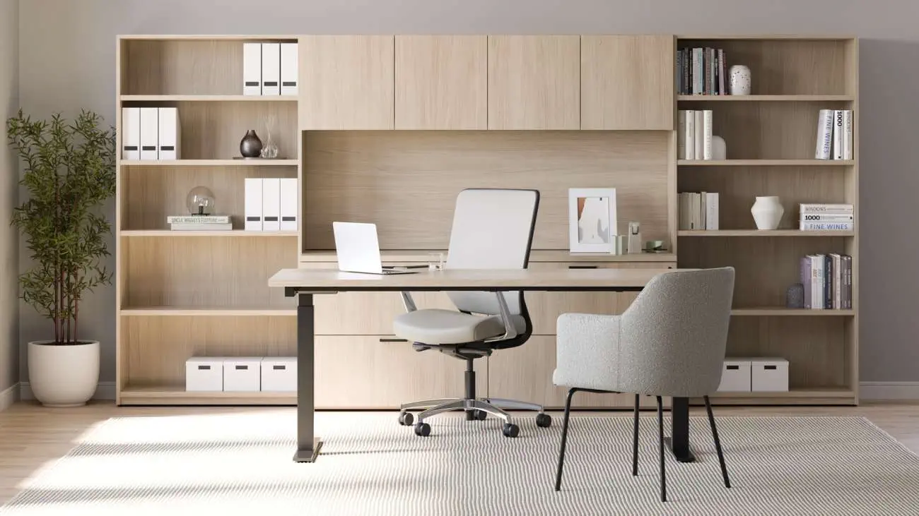 OFS Pulse desk with light wood bookcase wall and upper cabinets, featuring a minimalist workspace setup with task chair and guest chair in a contemporary office.
