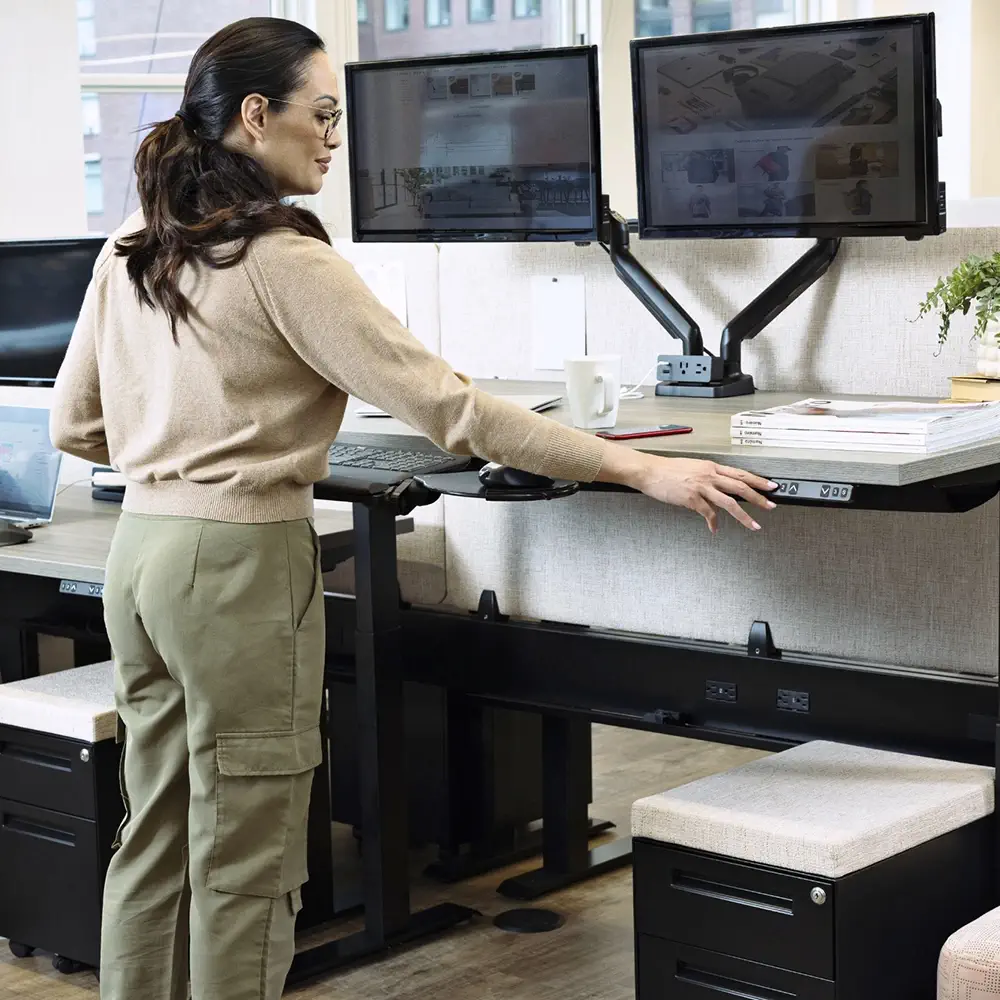 A person using a SitOnIt Surge height-adjustable desks in an open office.