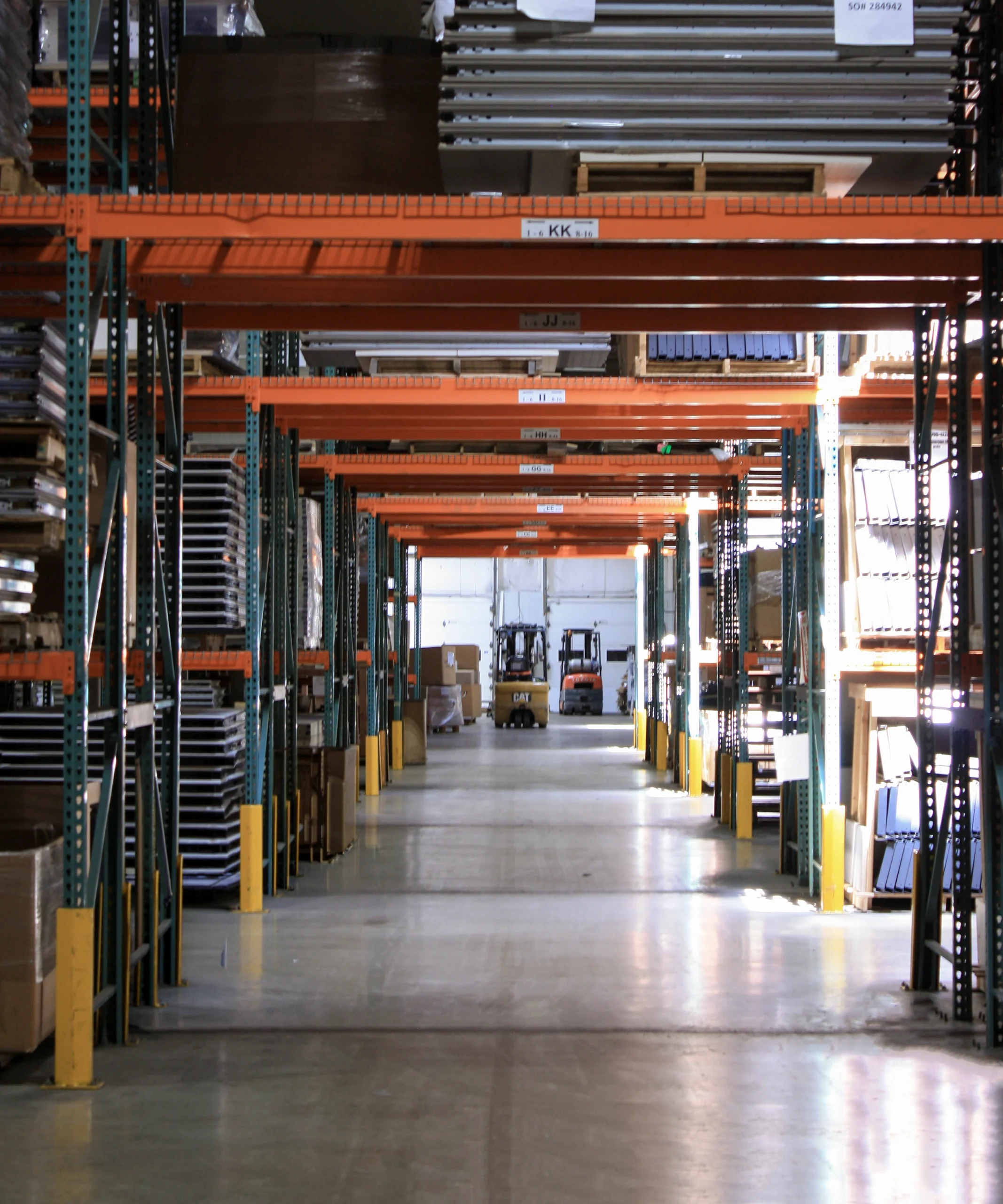 Warehouse aisle with industrial shelving and equipment for furniture remanufacturing.